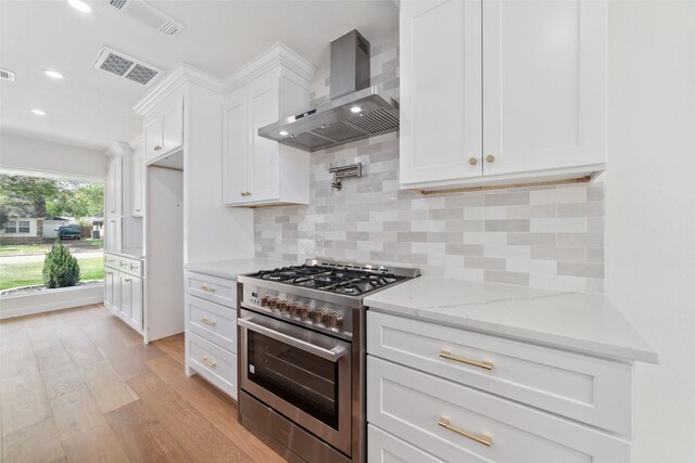 2618 Pine Village Dr, Houston, TX 77080 - kitchen with high end stainless steel range, wall chimney range hood, light wood-type flooring, white cabinetry, and recessed lighting