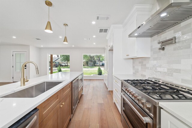 2618 Pine Village Dr, Houston, TX 77080 - kitchen with appliances with stainless steel finishes, wall chimney exhaust hood, a sink, light wood-style floors, and brown cabinetry