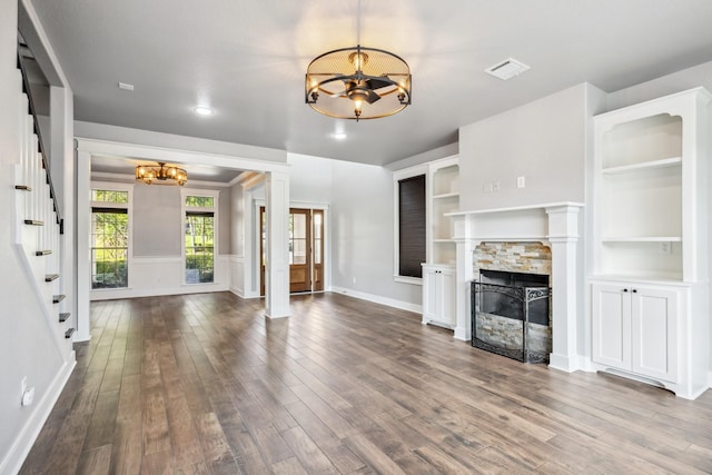 12336 Pebble View Dr, Conroe, TX 77304 - unfurnished living room featuring a chandelier, stairway, dark wood-style flooring, baseboards, and a stone fireplace