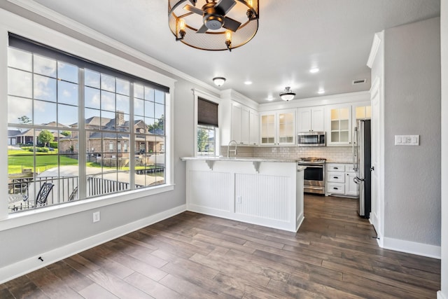 12336 Pebble View Dr, Conroe, TX 77304 - kitchen featuring appliances with stainless steel finishes, crown molding, a peninsula, glass insert cabinets, and baseboards