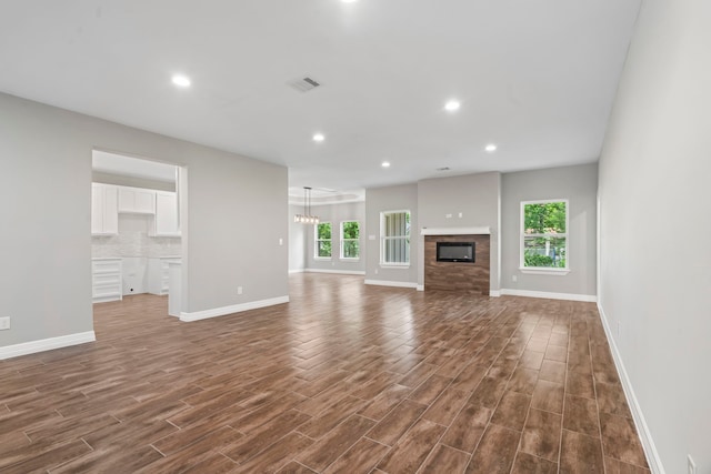 15608 Navajo Trl, Willis, TX 77378 - unfurnished living room featuring healthy amount of natural light, baseboards, dark wood-style flooring, recessed lighting, and a fireplace