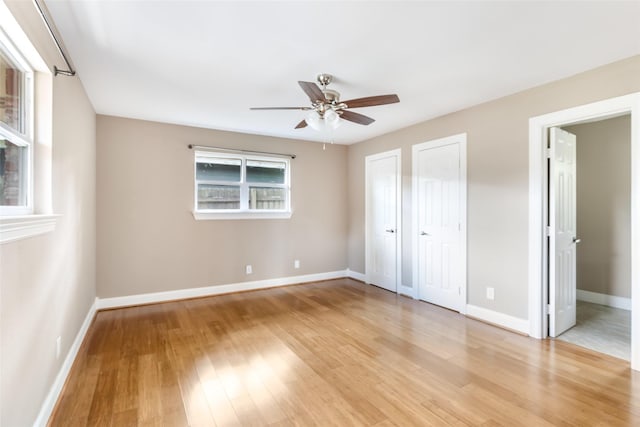 2198 N Winfree St, Dayton, TX 77535 - unfurnished bedroom featuring light wood finished floors, baseboards, multiple closets, and a ceiling fan
