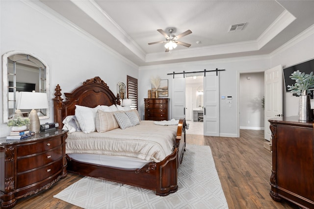 11 Bees Creek Ct, Missouri City, TX 77459 - bedroom featuring a barn door, wood finished floors, a tray ceiling, crown molding, and baseboards