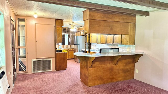 430 Hooks Rd, Livingston, TX 77351 - kitchen with light carpet, brown cabinets, a ceiling fan, a breakfast bar, and freestanding refrigerator