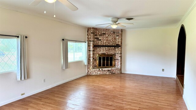 430 Hooks Rd, Livingston, TX 77351 - unfurnished living room featuring a ceiling fan, wood finished floors, arched walkways, ornamental molding, and a fireplace