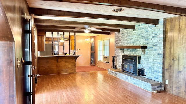 430 Hooks Rd, Livingston, TX 77351 - unfurnished living room featuring wood finished floors, wooden walls, heating unit, beamed ceiling, and a wood stove