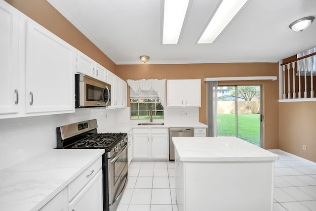 4907 Heritage Plains Dr, Friendswood, TX 77546 - kitchen with stainless steel appliances, light tile patterned floors, a sink, a kitchen island, and crown molding