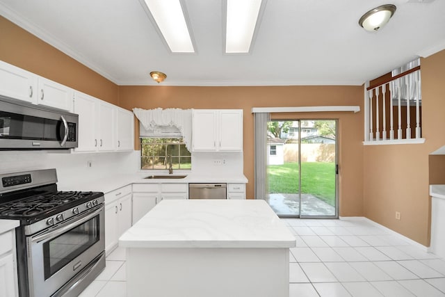 4907 Heritage Plains Dr, Friendswood, TX 77546 - kitchen with appliances with stainless steel finishes, a sink, white cabinets, light tile patterned floors, and ornamental molding