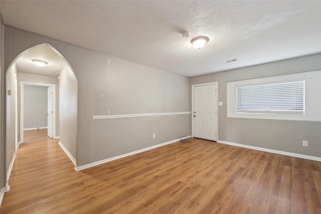 9270 Mclean St, Beaumont, TX 77707 - unfurnished room with light wood-type flooring, a textured ceiling, arched walkways, and baseboards
