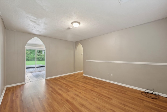 9270 Mclean St, Beaumont, TX 77707 - unfurnished room with arched walkways, light wood finished floors, a textured ceiling, and baseboards