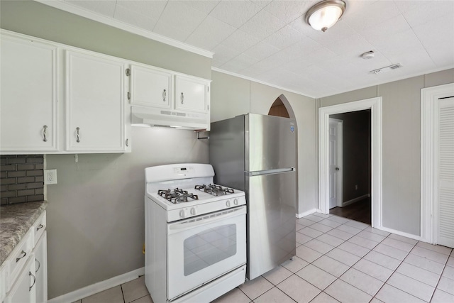 9270 Mclean St, Beaumont, TX 77707 - kitchen featuring white range with gas cooktop, under cabinet range hood, light tile patterned floors, freestanding refrigerator, and white cabinets