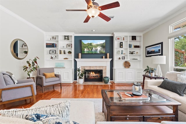 7818 Palm Brook Ct, Houston, TX 77095 - living room with wood finished floors, a ceiling fan, built in shelves, a fireplace, and crown molding