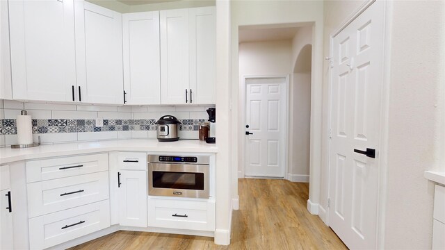 28511 E Benders Landing Blvd, Spring, TX 77386 - kitchen with stainless steel oven, decorative backsplash, light wood-style floors, light countertops, and white cabinetry