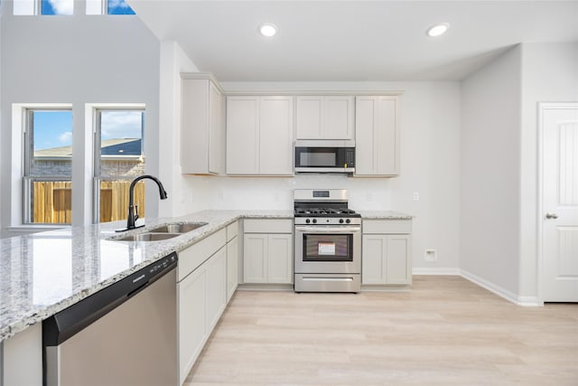 1039 Lilly Ln, Bellville, TX 77418 - kitchen featuring appliances with stainless steel finishes, a sink, light wood-style flooring, light stone counters, and recessed lighting
