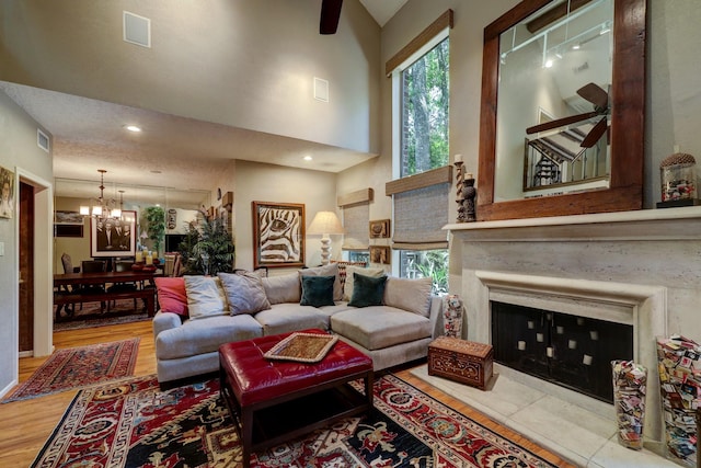 322 Sugarberry Cir, Houston, TX 77024 - living room featuring a chandelier, a towering ceiling, wood finished floors, a ceiling fan, and a tile fireplace