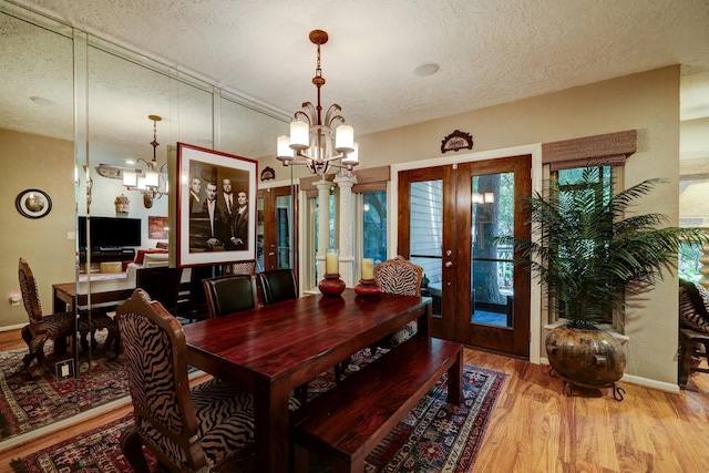 322 Sugarberry Cir, Houston, TX 77024 - dining space featuring a chandelier, french doors, a textured ceiling, wood finished floors, and baseboards