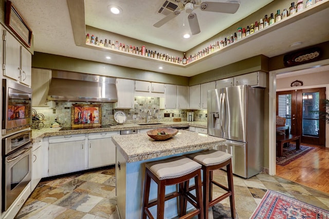 322 Sugarberry Cir, Houston, TX 77024 - kitchen with appliances with stainless steel finishes, a sink, wall chimney range hood, a ceiling fan, and tasteful backsplash