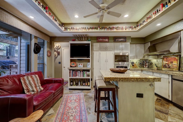 322 Sugarberry Cir, Houston, TX 77024 - kitchen featuring a ceiling fan, a kitchen island, a kitchen breakfast bar, backsplash, and stainless steel microwave