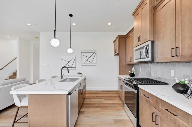 4703 Oats St Unit B, Houston, TX 77020 - kitchen with appliances with stainless steel finishes, a sink, a breakfast bar, light wood-style flooring, and decorative backsplash