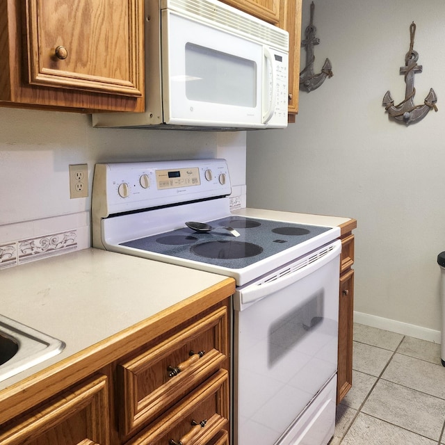 278 Shelter Cove Dr, Livingston, TX 77351 - kitchen featuring white appliances, brown cabinets, light countertops, and light tile patterned floors