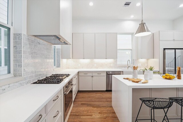 506 Parker St, Houston, TX 77007 - kitchen with stainless steel appliances, custom exhaust hood, a breakfast bar area, tasteful backsplash, and pendant lighting
