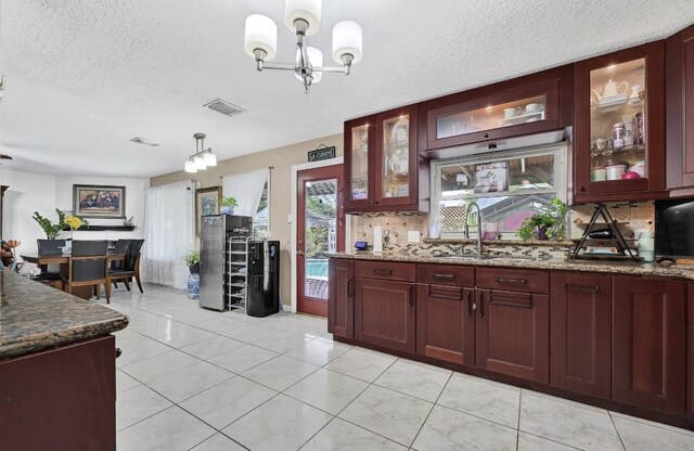 15133 Elstree Dr, Channelview, TX 77530 - kitchen with decorative backsplash, a sink, a textured ceiling, decorative light fixtures, and a chandelier