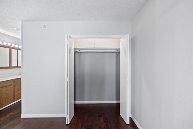 283 Sam Loop, Houston Loop, Point Blank, TX 77364 - unfurnished bedroom featuring a closet, dark wood-style floors, a textured ceiling, baseboards, and connected bathroom