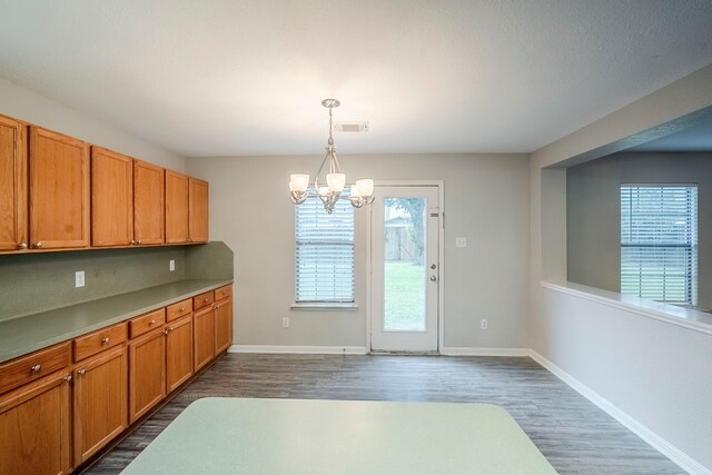 21106 Scenic Bluff Ln, Humble, TX 77338 - kitchen featuring a chandelier, dark wood-style floors, brown cabinetry, baseboards, and hanging light fixtures