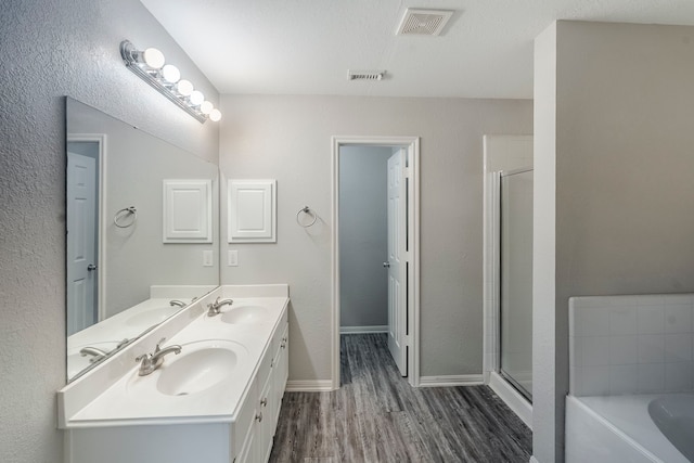 21106 Scenic Bluff Ln, Humble, TX 77338 - full bath featuring wood finished floors, double vanity, a bath, a stall shower, and baseboards
