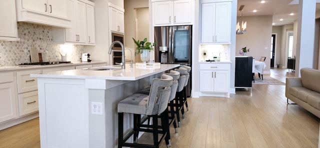 25014 Ryleigh Cove Cir, Tomball, TX 77375 - kitchen with a sink, light wood finished floors, white cabinets, a kitchen bar, and recessed lighting