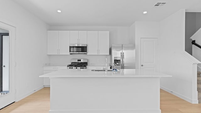 1823 Revolution Way, Missouri City, TX 77489 - kitchen featuring appliances with stainless steel finishes, light wood finished floors, white cabinets, an island with sink, and recessed lighting