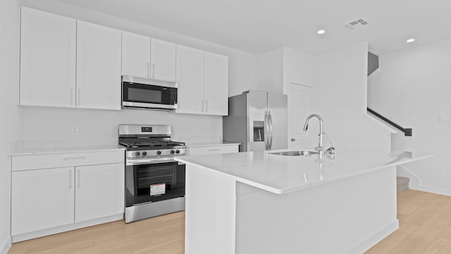 1823 Revolution Way, Missouri City, TX 77489 - kitchen with appliances with stainless steel finishes, light wood-style floors, white cabinets, recessed lighting, and a kitchen island with sink