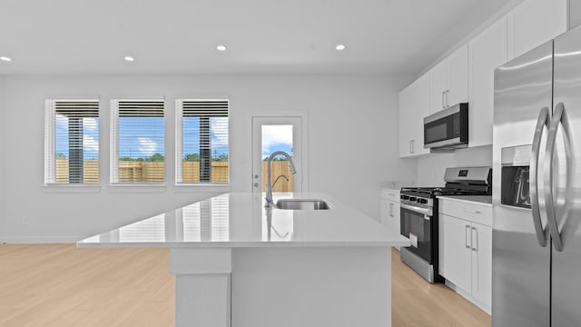 1823 Revolution Way, Missouri City, TX 77489 - kitchen featuring stainless steel appliances, light wood-type flooring, an island with sink, recessed lighting, and white cabinetry