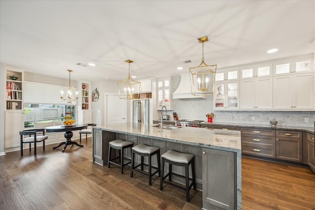 29303 Kellys Falls Ct, Katy, TX 77494 - kitchen featuring a sink, a chandelier, custom exhaust hood, light stone countertops, and recessed lighting