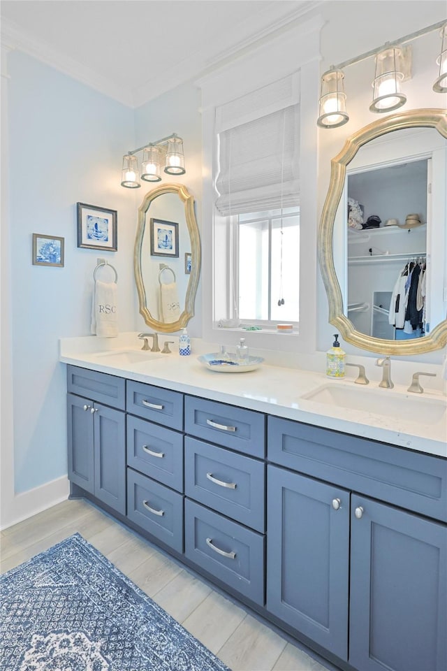 23125 Gulf Dr, Galveston, TX 77554 - bathroom featuring double vanity, wood finished floors, a walk in closet, and ornamental molding
