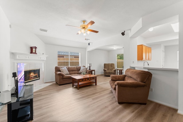 6107 Villa Hills Dr, Houston, TX 77066 - living area featuring a fireplace, light wood finished floors, a ceiling fan, arched walkways, and healthy amount of natural light