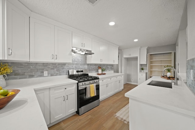 5347 Laurel Creek Way, Houston, TX 77017 - kitchen featuring stainless steel range with gas stovetop, a sink, light wood-style flooring, under cabinet range hood, and white cabinets