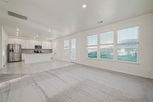 7106 Escondido Dr, Rosharon, TX 77583 - unfurnished living room with light carpet, light tile patterned floors, recessed lighting, and baseboards