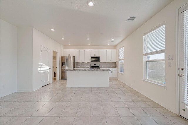 7106 Escondido Dr, Rosharon, TX 77583 - kitchen with stainless steel appliances, white cabinetry, a kitchen island with sink, light tile patterned flooring, and recessed lighting