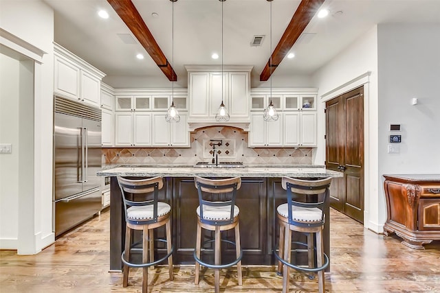 8305 Will Jordan Pkwy, Bellaire, TX 77401 - kitchen featuring stainless steel built in fridge, beam ceiling, a center island with sink, white cabinets, and light wood finished floors