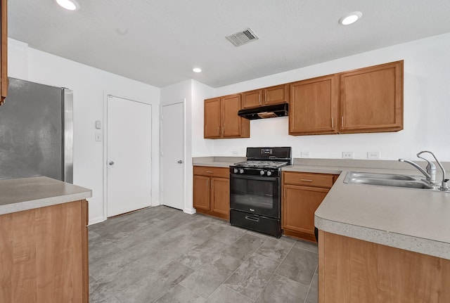 19311 Old Finch Ct, Houston, TX 77073 - kitchen with freestanding refrigerator, a sink, black range with gas stovetop, under cabinet range hood, and light countertops