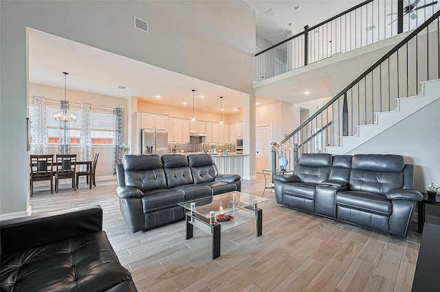 13811 Via Toluca Trl, Cypress, TX 77433 - living room with a chandelier, a high ceiling, light wood finished floors, stairs, and baseboards