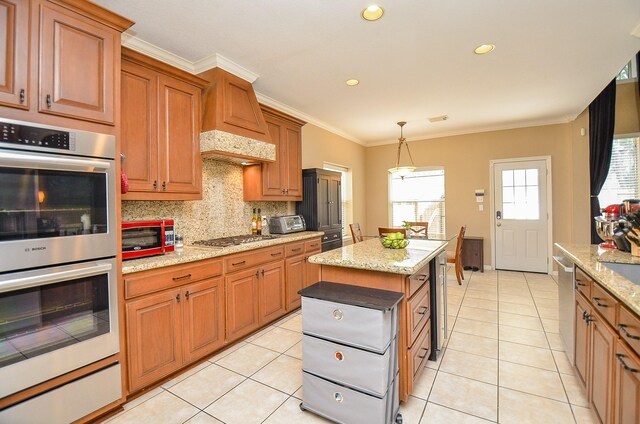 13023 Forester Canyon Ln, Sugar Land, TX 77498 - kitchen with stainless steel appliances, backsplash, crown molding, brown cabinetry, and hanging light fixtures