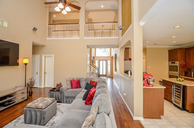 13023 Forester Canyon Ln, Sugar Land, TX 77498 - living area with beverage cooler, a ceiling fan, arched walkways, crown molding, and baseboards
