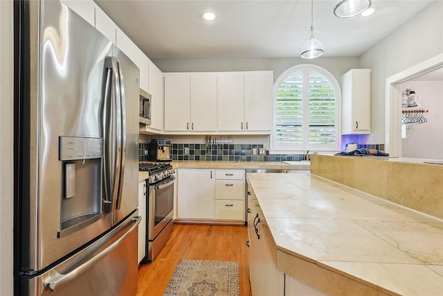 2505 Brinkman St, Houston, TX 77008 - kitchen featuring stainless steel appliances, light wood-style floors, white cabinetry, hanging light fixtures, and recessed lighting