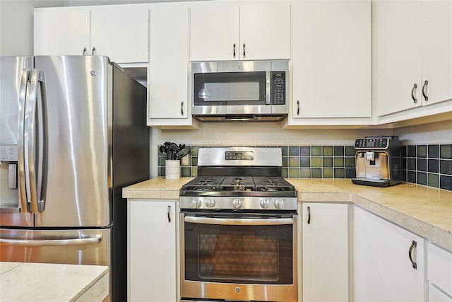 2505 Brinkman St, Houston, TX 77008 - kitchen with appliances with stainless steel finishes, light countertops, white cabinetry, and decorative backsplash