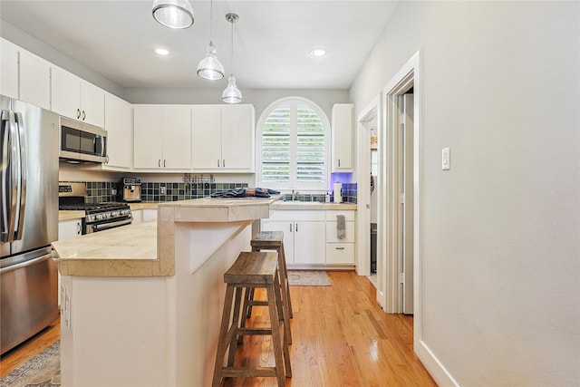 2505 Brinkman St, Houston, TX 77008 - kitchen featuring stainless steel appliances, a kitchen island, light wood-type flooring, white cabinets, and recessed lighting