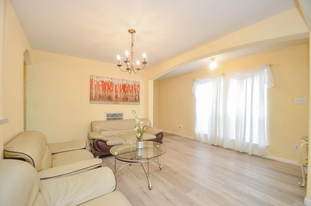 7102 Biton Dr, Houston, TX 77083 - living room featuring arched walkways, a chandelier, light wood-style flooring, and baseboards