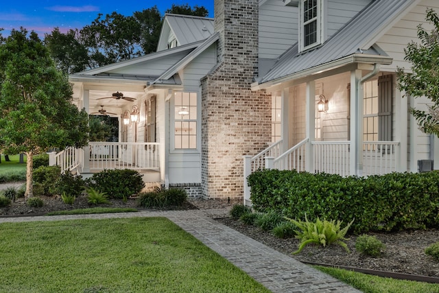 5926 Bit Pl, Baytown, TX 77523 - exterior entry at dusk featuring a porch, ceiling fan, a lawn, a chimney, and metal roof