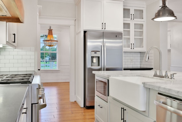 5926 Bit Pl, Baytown, TX 77523 - kitchen with appliances with stainless steel finishes, light wood-style floors, white cabinets, a sink, and hanging light fixtures